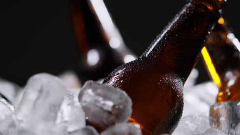 Nahaufnahme-Einer-Person,-Die-Eine-Gekühlte-Glasflasche-Kaltes-Bier-Oder-Alkoholfreie-Getränke-Aus-Einem-Mit-Eis-Gefüllten-Eimer-Vor-Schwarzem-Hintergrund-Nimmt-1